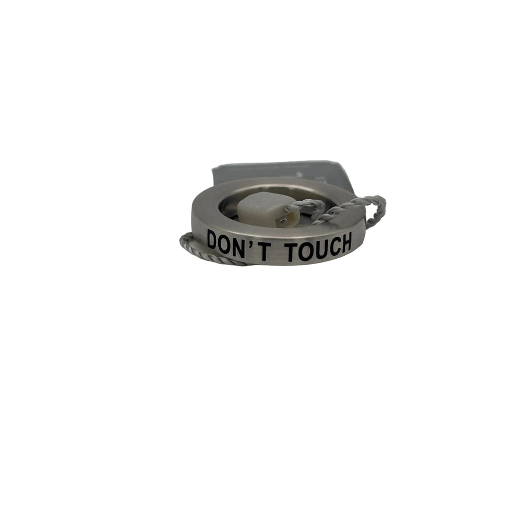 Anello ciondolo Breil Stones in acciaio con incisione nera 'DON'T TOUCH'. L'oggetto è mostrato con l'etichetta originale Breil Stones e il sigillo di garanzia grigio, evidenziando l'autenticità del prodotto.