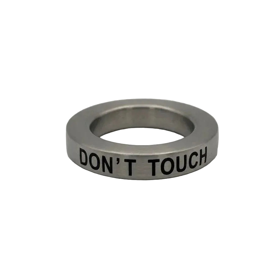 Primo piano pulito dell'anello a fascia Breil Stones utilizzabile come ciondolo. La foto mette in risalto la finitura in acciaio e la scritta nera 'DON'T TOUCH' .